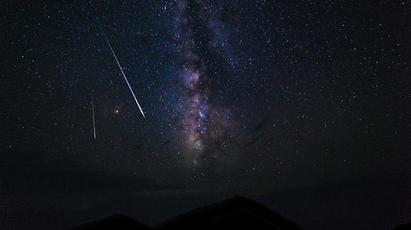 Two meteor trails against a starry background in the night sky.