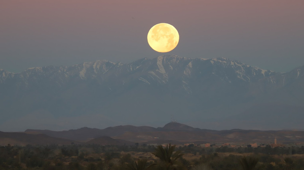 A Full Moon sets behind the Atlas Mountains in Morocco.