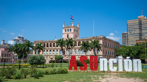 Historic building with the Paraguayan flag flying on top and "Asunción" spelled out in large red and white letters in front of it.