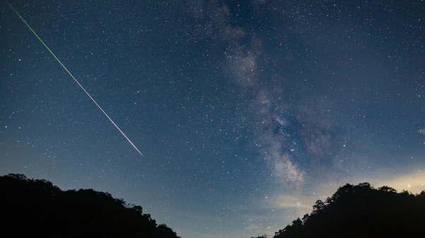 A shooting star streaks across the night sky.